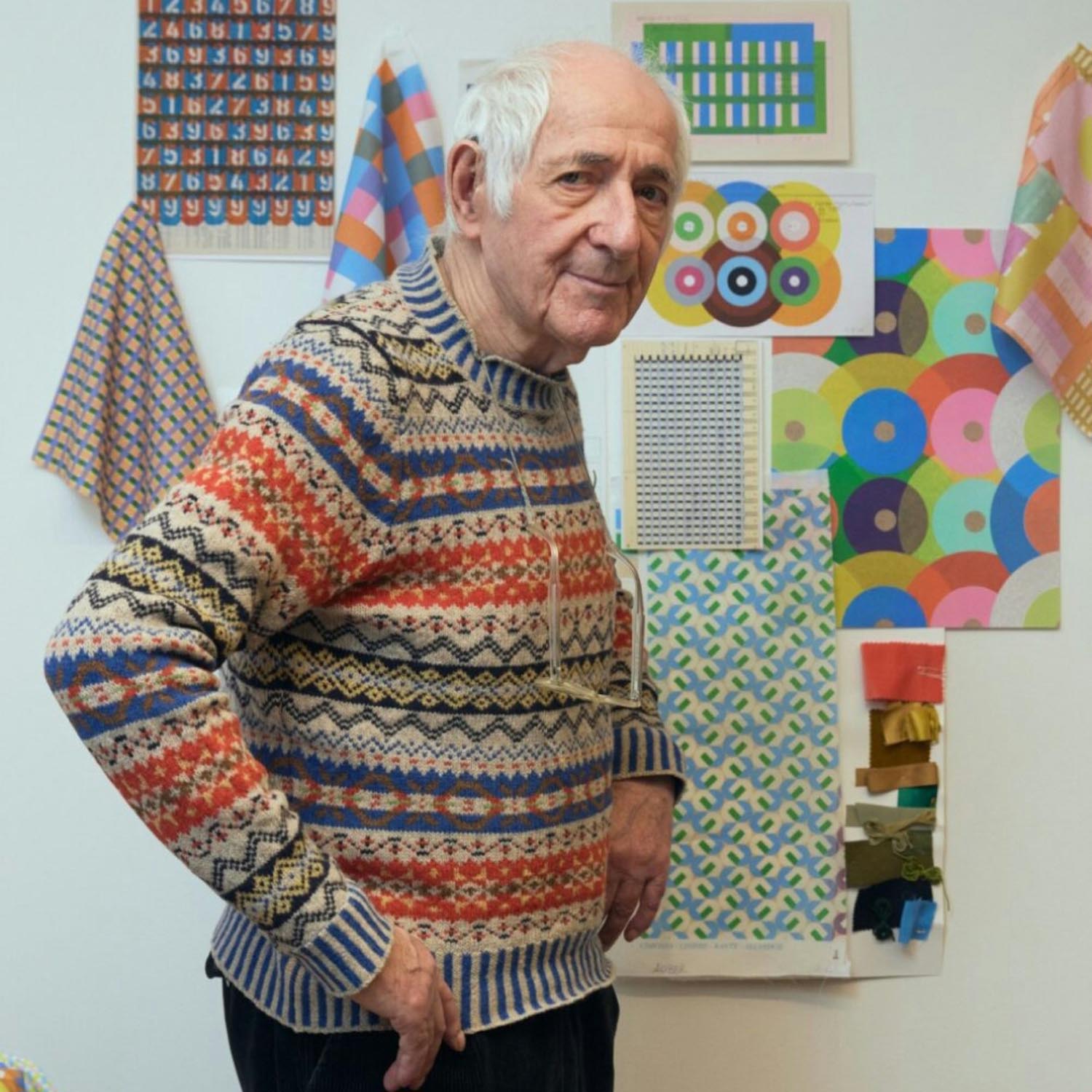 A portrait of Karel Martens in front of samples of his work