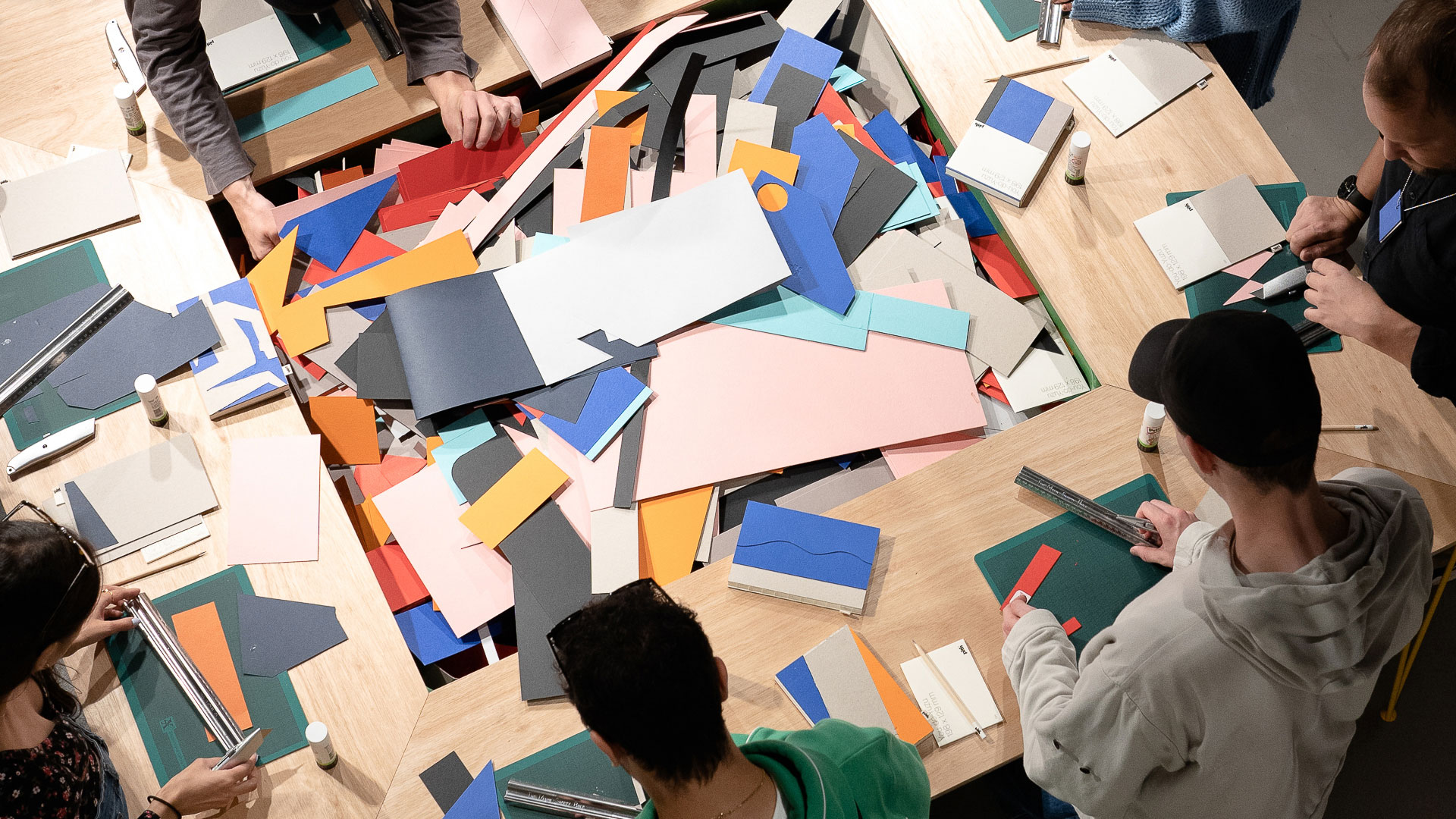 Participants making notebooks, working on a big table with lots of paper offcuts