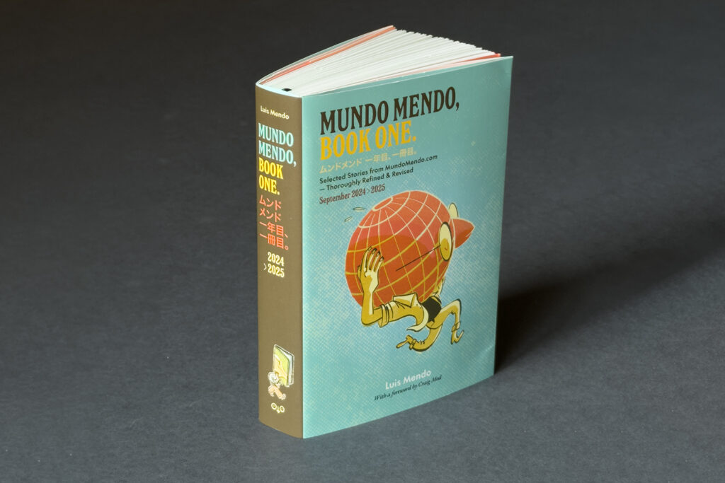 A photograph of Mundo Mendo Book 1, by Luis Mendo. An A6 format 272 page book with an illustrated cover showing a man with a head in the shape of a globe running along at speed.