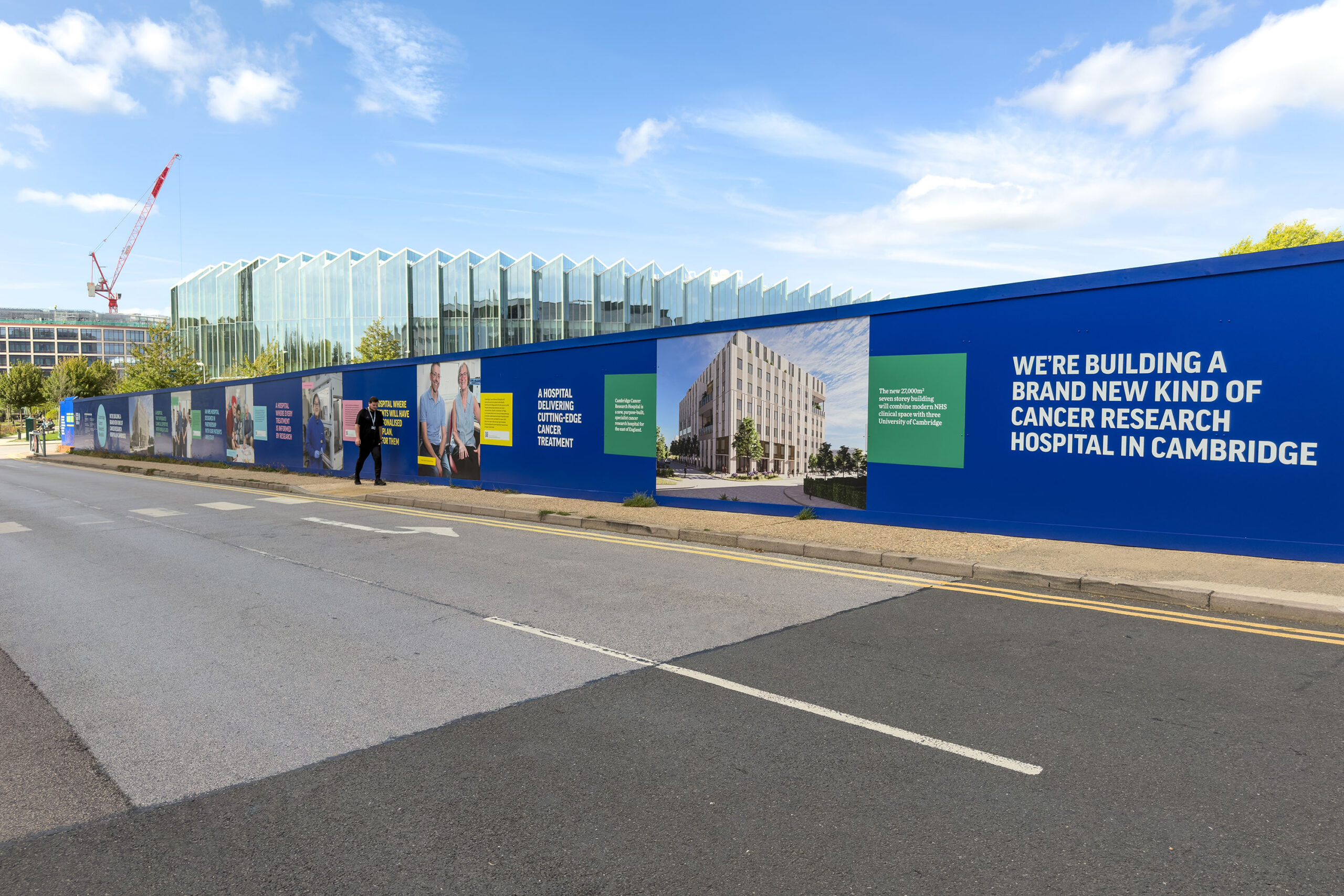 A hoarding for the Cambridge Cancer Research Hospital, featuring text and images about the hospital